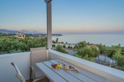 una mesa blanca con un bol de fruta en el balcón en Fata Morgana Studios & Apartments, en Frangokastello