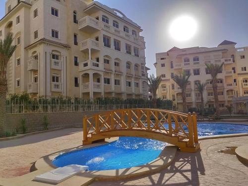a wooden bridge over a pool in front of a building at Ramco For Furnished Apartments And Accommodation Compound Leila in Cairo