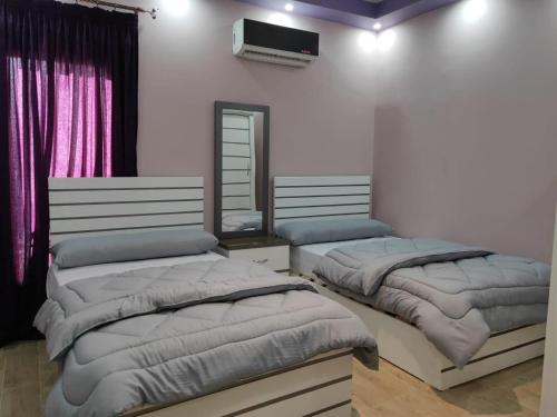 a bedroom with two beds and a tv on the wall at Ramco For Furnished Apartments And Accommodation Compound Leila in Cairo