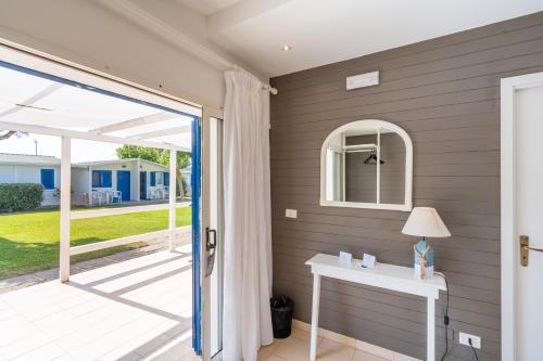 uma porta para um pátio com uma mesa e uma janela em Le Dune Beach Club em Torre Faro