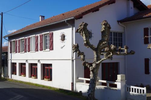 a white building with red windows and a tree at Maison Elizondoa - chambres, restaurant et SPA in Masparraute