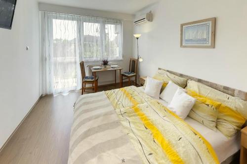 a bedroom with a large bed with yellow and white pillows at Hajnalház Apartments in Balatonfüred