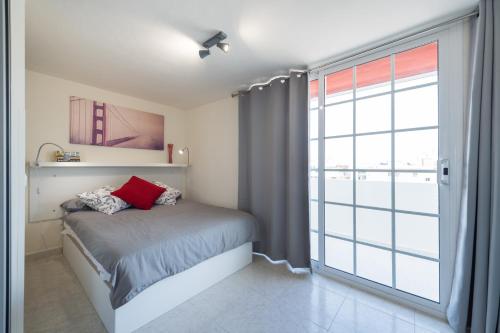 1 dormitorio con cama y ventana grande en Living Las Canteras Homes - WORKOUT & FREE BIKES, en Las Palmas de Gran Canaria