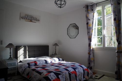 a bedroom with a bed with a quilt and a window at Maison Elizondoa - chambres, restaurant et SPA in Masparraute