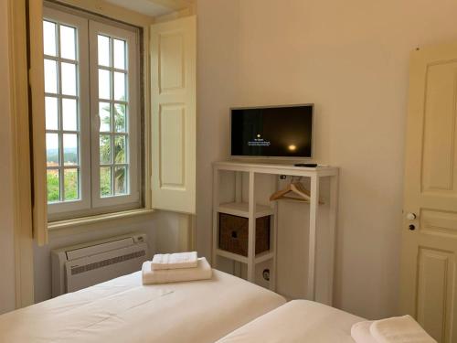 a bedroom with a bed and a flat screen tv at Entire House - Romantic Vintage Cottage in Sintra