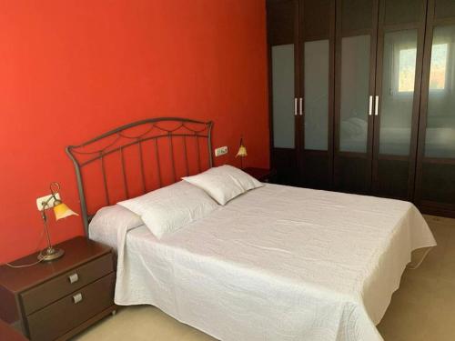 - une chambre avec un lit blanc et un mur rouge dans l'établissement Apartamentos San Miguel 2, à Almerimar