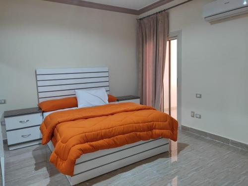 a bedroom with a bed with an orange blanket at Ramco For Furnished Apartments And Accommodation Compound Leila in Cairo