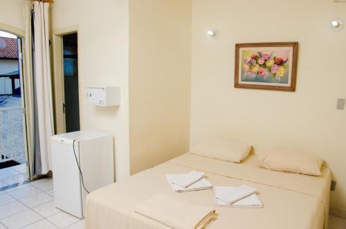 a white room with a bed and a picture on the wall at Pousada Portal do Mar in Cabo Frio
