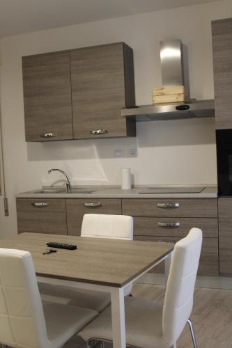 een keuken met een houten tafel en witte stoelen bij Bilocale Sirio-Intero appartamento ad uso esclusivo by Appartamenti Petrucci by Appartamenti Petrucci in Foligno