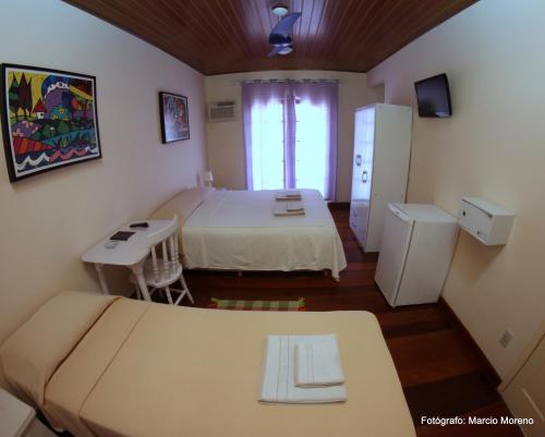 a small room with two beds and a refrigerator at Pousada Portal do Mar in Cabo Frio