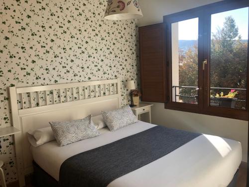 1 dormitorio con cama blanca y ventana en Casa de Navalhorno Valsain, en La Pradera de Navalhorno
