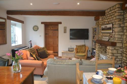a living room with couches and a stone wall at Church Cottage Barn in Longborough