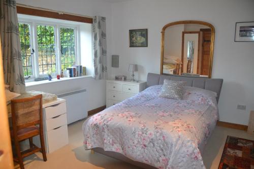 ein Schlafzimmer mit einem Bett, einer Kommode und einem Spiegel in der Unterkunft Church Cottage Barn in Longborough