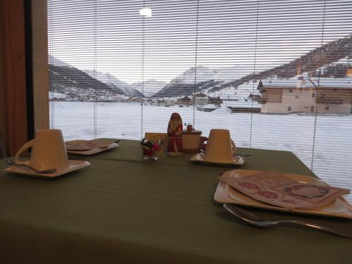 una mesa con platos y utensilios en una mesa con ventana en B&B Ecohotel Chalet des Alpes, en Livigno