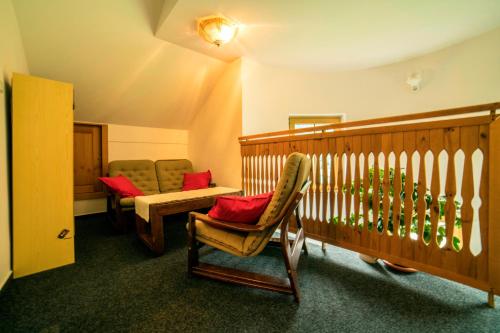 ヴルフラビーにあるPension 222 - Family rooms in Vrchlabiの椅子2脚と赤い枕付きのベビーベッド1台が備わる客室です。
