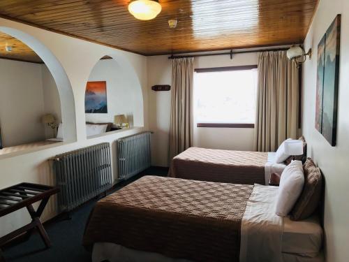 Una habitación de hotel con dos camas y una ventana. en Hotel Ushuaia, en Ushuaia