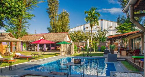 einen Pool mit Tischen und Stühlen neben einem Gebäude in der Unterkunft La Maison in Toamasina