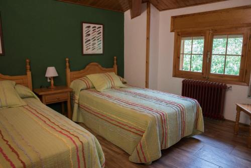 Dos camas en un dormitorio con paredes verdes. en Casa Rural Los Jamones, en Arroyo Frío