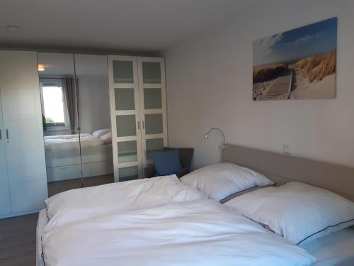 een slaapkamer met een bed met witte lakens en een spiegel bij Küstenbude No.6 Büsum Zentrum in Büsum