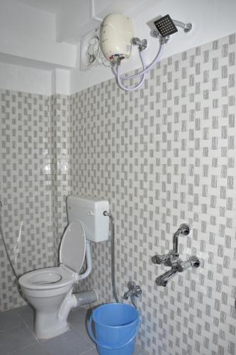 a bathroom with a toilet with a shower and a bucket at The Lotus Home in Port Blair