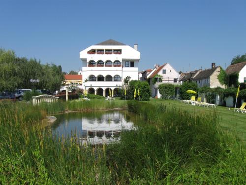 a large white house with a pond in front of it at Das-Schmidt Privathotel in Mörbisch am See