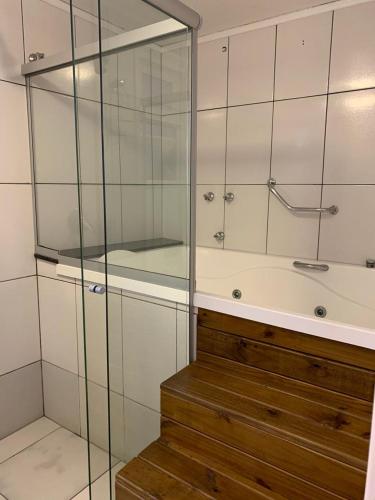 a glass shower in a bathroom with a tub at Bellagio Mini Resort - no coração de Gramado in Gramado