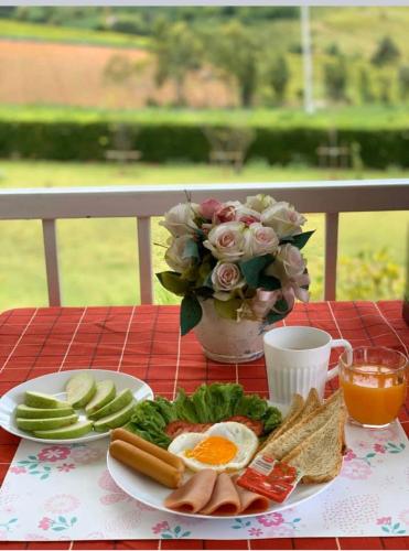einen Tisch mit einem Frühstücksteller und einer Vase mit Blumen in der Unterkunft Misty English Cottage in Ban Non Na Yao
