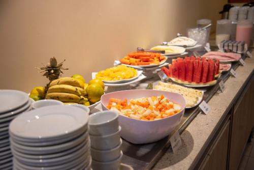 a buffet with plates and bowls of fruit and vegetables at Getúllio Hotel in Cuiabá