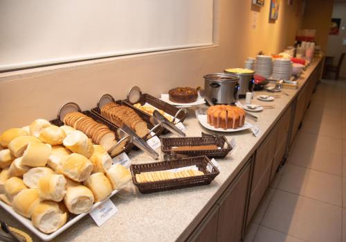 a buffet line with different types of bread and pastries at Getúllio Hotel in Cuiabá