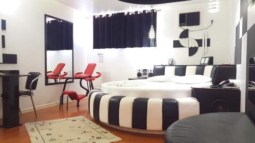 a salon with a round table and red chairs at L'acqua Motel Express in Ponta Grossa