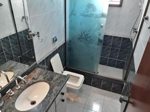 ein Bad mit einem Waschbecken, einer Dusche und einem WC in der Unterkunft Apartamento para 6 pessoas a 10m da praia in Praia Grande