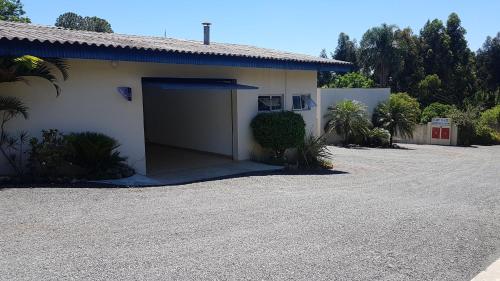 a white building with a garage and a driveway at L'acqua Motel Express in Ponta Grossa