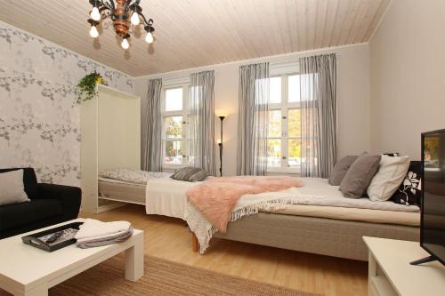 a bedroom with a bed and a couch and windows at Idyllic central wooden house apartment in Pori