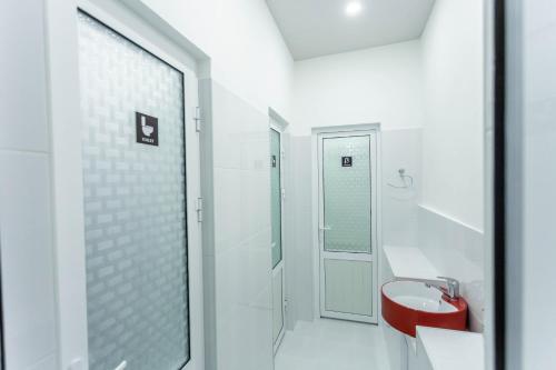 a white bathroom with a red sink and a shower at Registan Hostel in Samarkand