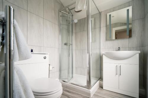 a bathroom with a shower, toilet, sink and tub at The Clarendon Hotel in London