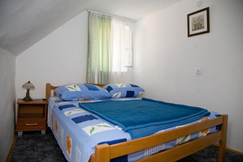 Schlafzimmer mit einem Bett mit blauer Bettwäsche und einem Fenster in der Unterkunft Apartment Matejuška in Split