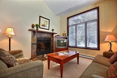 a living room with a fireplace and a coffee table at Aiglon by Rendez-Vous Mont-Tremblant in Mont-Tremblant