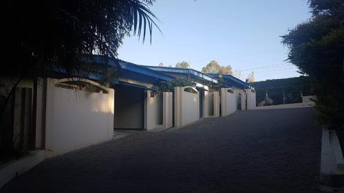 an empty alley with white buildings and a palm tree at L'acqua Motel Express in Ponta Grossa