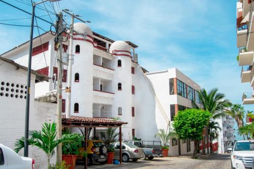 a white building with cars parked in front of it at Petit Hotel Pilitas in Puerto Vallarta
