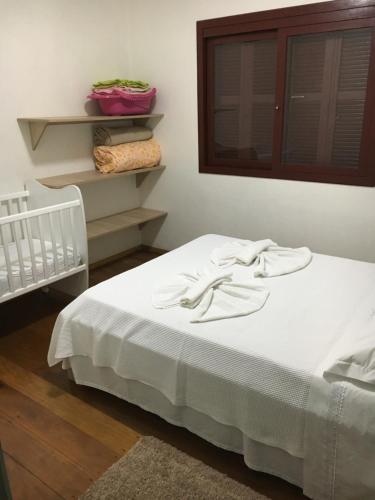 Una cama con sábanas blancas y una ventana en una habitación en Apartamento a DUAS quadras do Centro, en Gramado