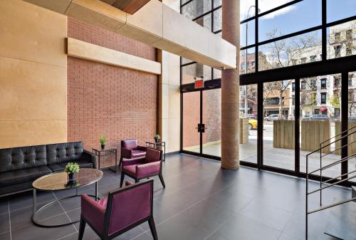 a lobby with purple chairs and tables and windows at Orchard Street Hotel in New York