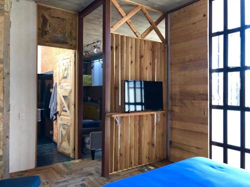 a room with a wooden wall with a tv and a bedroom at Canela Fina - Adults Only in San Miguel de Allende