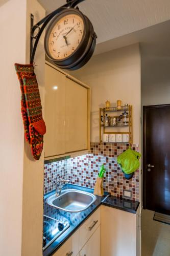 eine Küche mit Spüle und einer Uhr an der Wand in der Unterkunft New Gudauri M&N in Gudauri