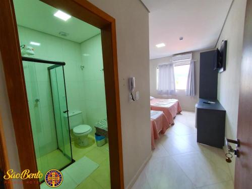 um quarto com uma cama e uma casa de banho com um espelho em São Bento Palace Hotel em Aparecida
