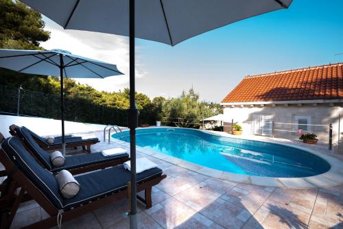 a swimming pool with two chairs and an umbrella at Villa Katja in Sumartin