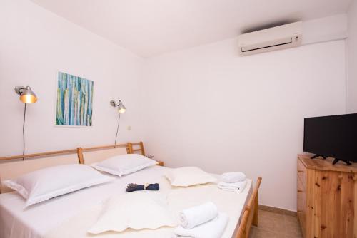 a bedroom with a bed with white sheets and a tv at Villa Katja in Sumartin