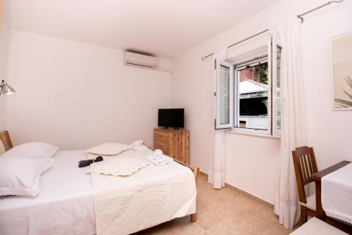 a white bedroom with a bed and a window at Villa Katja in Sumartin