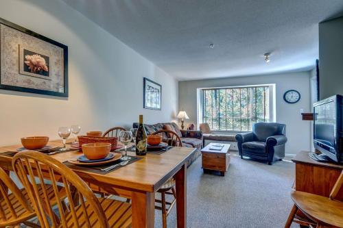 a living room with a table and chairs and a television at Town Plaza Suites by Golden Dreams in Whistler