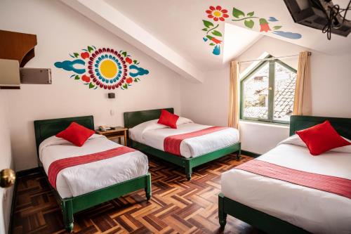 a room with two beds with red pillows and a window at Cusco Plaza Nazarenas in Cusco