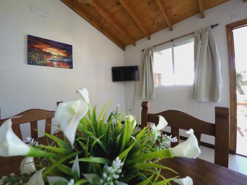 una mesa de comedor con flores blancas. en Cabañas Victoria en Mar de las Pampas